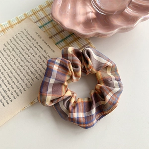 Close-up of vintage plaid scrunchie with warm earth-tone patterns on aesthetic background