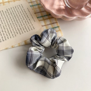 Close-up of blue and white plaid scrunchie with soft fabric texture on a desk