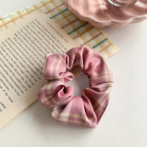 Close-up of pink plaid oversized scrunchie hair tie with soft fabric texture and check pattern