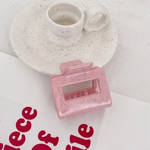 Vue détaillée d'une pince à cheveux carrée rose mat avec texture en résine mouchetée