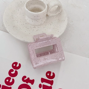 Détail d'une pince à cheveux rose mouchetée style terrazzo sur une assiette céramique