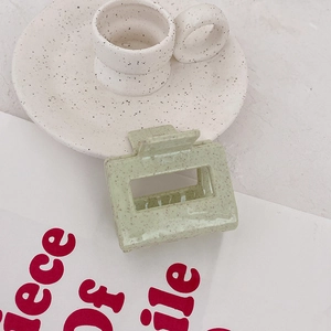 Vue détaillée d'une pince à cheveux carrée vert clair avec texture mouchetée