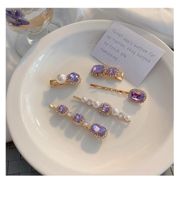 Detailed set of purple rhinestone and pearl hair clips on a white display plate