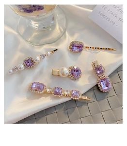 Detail view of purple crystal hair clips with imitation pearls on golden alloy base