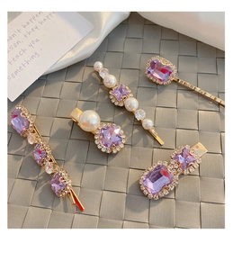 Detail of 5-piece purple crystal and pearl hair clip set with golden metal finish