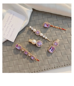 Close-up of four vintage purple crystal and pearl hair clips on a silk background