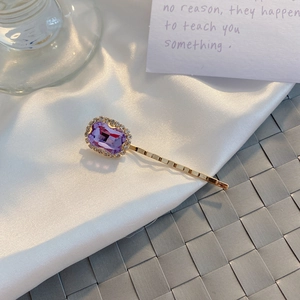 Detail of vintage hair clip featuring a purple rhinestone gemstone and pearl accents