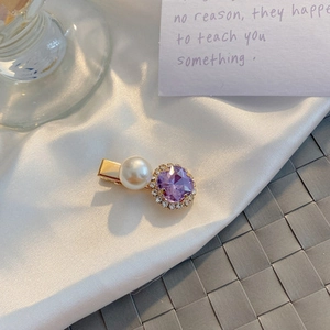 Macro detail of vintage purple crystal and pearl hair clip on white satin fabric