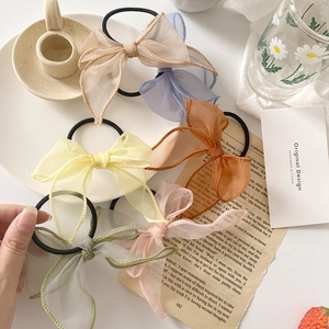 Détail de six chouchous nœuds en organza pastel présentés avec des accessoires vintage