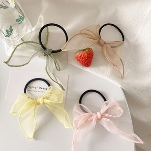 Gros plan de quatre chouchous nœuds en organza en vert pastel, abricot, jaune et rose