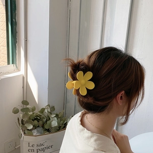 Detailansicht der gelben Blumen-Haarklammer im Haar mit matter Oberflächenstruktur