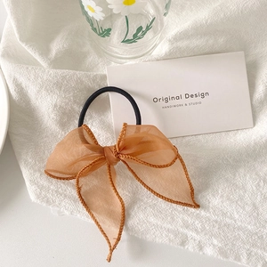 Texture détaillée du chouchou en organza caramel avec rubans sur lin blanc pur