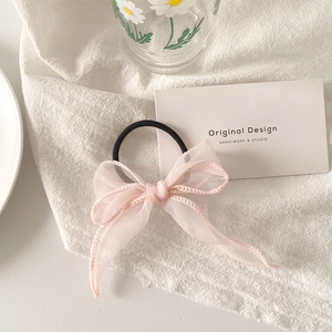 Détail d'un chouchou en organza rose avec nœud papillon sur tissu en lin texturé