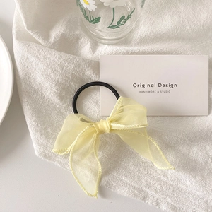 Gros plan d'un chouchou noeud en organza jaune clair avec coutures fines et texture