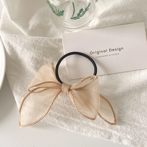 Détail d'un chouchou en organza champagne avec nœud élégant et finitions de couture
