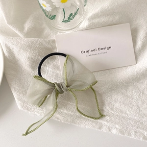 Détail d'un chouchou en organza vert clair avec des bords cousus délicats
