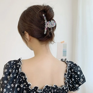 Pince à cheveux en acétate avec motif d'encre colorée montrée sur cheveux de femme