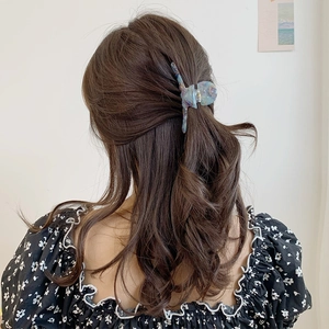 Vue détaillée d'une grande pince à cheveux sirène en acétate avec texture marbrée bleue