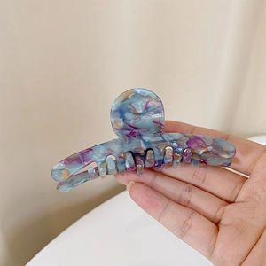 Gros plan d'une pince à cheveux en acétate aux motifs marbrés bleus et violets