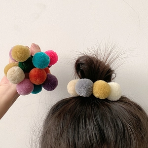 Detail of colorful plush pom pom hair ties showing soft texture and elastic hold in hair