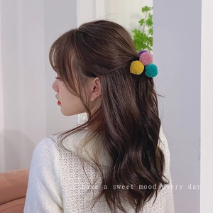 Detail of colorful pom-pom hair ties on model's hairstyle in soft candy colors