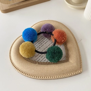 Detailed view of colorful plush pom-pom hair ties with high elastic black rubber bands