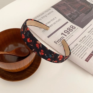Detail eines Blumen-Haarreifens mit Vintage-Muster auf weißem Tisch mit Deko