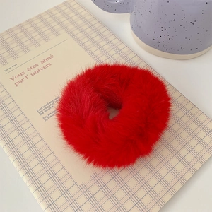 Close-up of soft red plush scrunchie with a fuzzy texture on a cozy background