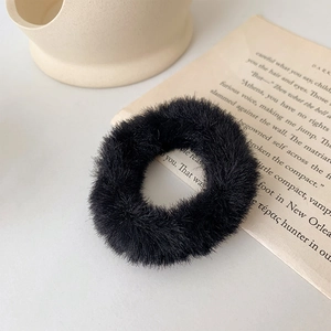 Vue détaillée d'un chouchou noir en fausse fourrure sur un fond de papier vintage