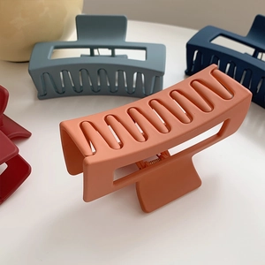 Close-up of matte rectangular hair claw clips in vibrant orange and blue colors