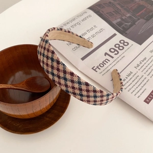 Detailaufnahme von kariertem Cord-Stirnband auf Vintage-Zeitungsuntergrund