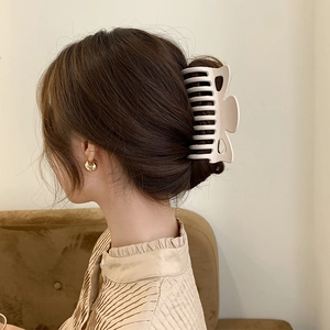 Elegant matte large claw clip holding a bun in a natural cream finish on model