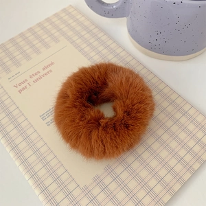Detail shot of a soft caramel brown plush scrunchie on a cozy home desk setup