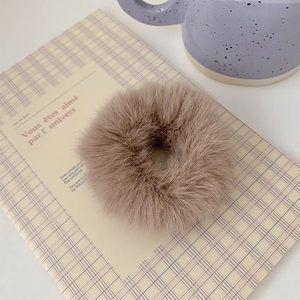Detail of light brown plush faux fur scrunchie on a notebook with a cozy texture