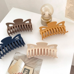 Detail showing four matte hair claws in dark coffee, ginger, navy, and cream colors