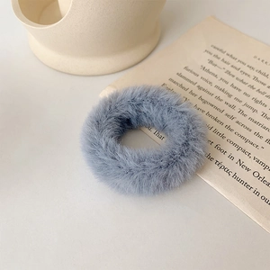 Détail macro d'un chouchou en fausse fourrure bleu-gris doux sur un fond de papier décoratif
