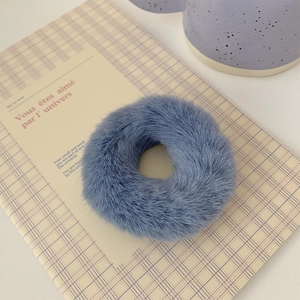 Close-up of soft blue plush hair scrunchie on vintage plaid notebook with gentle lighting