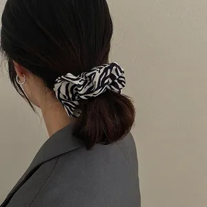 Chic zebra pattern hair scrunchie and silver hoop earring worn by a model in casual blazer