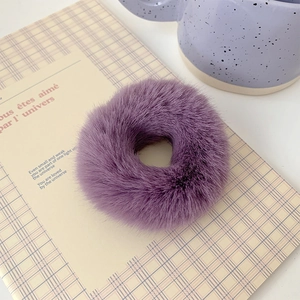 Close-up of soft purple faux fur scrunchie on a yellow checkered notebook background