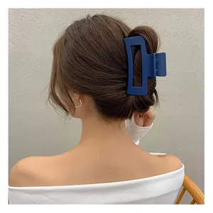 Detail of a large matte navy blue rectangular hair claw clip styling a low bun on long hair