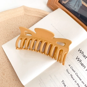 Macro detail of large matte ginger hair claw clip on book for elegant styling