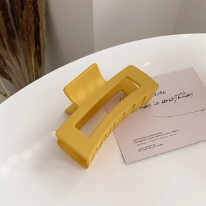 Macro view of a large rectangular matte yellow hair claw clip with a hollow design