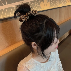 Detailed view of leopard print hair scrunchie styled on a woman's bun hairstyle