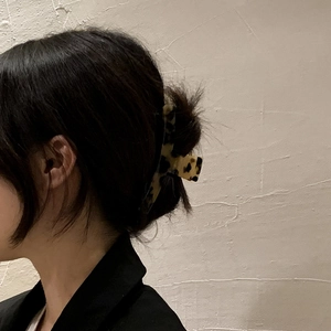 Detail of a large leopard print hair claw clip securing an elegant updo hairstyle