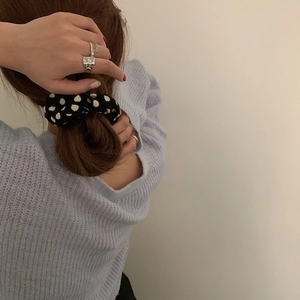 Detailed view of a black and white polka dot fabric scrunchie styled in a low ponytail