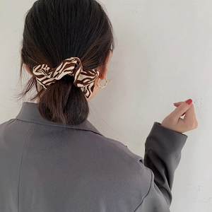 Detailed view of animal print satin scrunchie styled on a low bun hairstyle