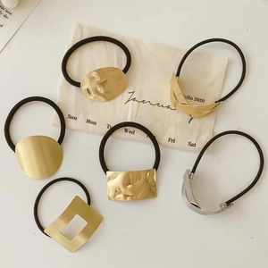 Gros plan d'élastiques à cheveux métalliques minimalistes dorés et argentés sur lin