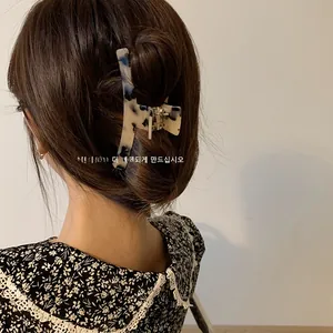 Detail view of large marble pattern hair claw clip securing a classic French updo hairstyle
