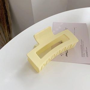 Detail view of large rectangular pale yellow matte hair claw clip with cutout design