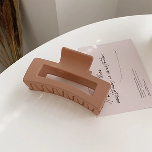 Detail of a large matte orange rectangular hair claw clip for thick hair styling